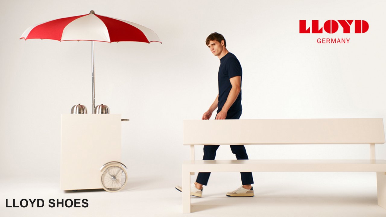 A man walking behind a bench towards a cart and looking at the camera