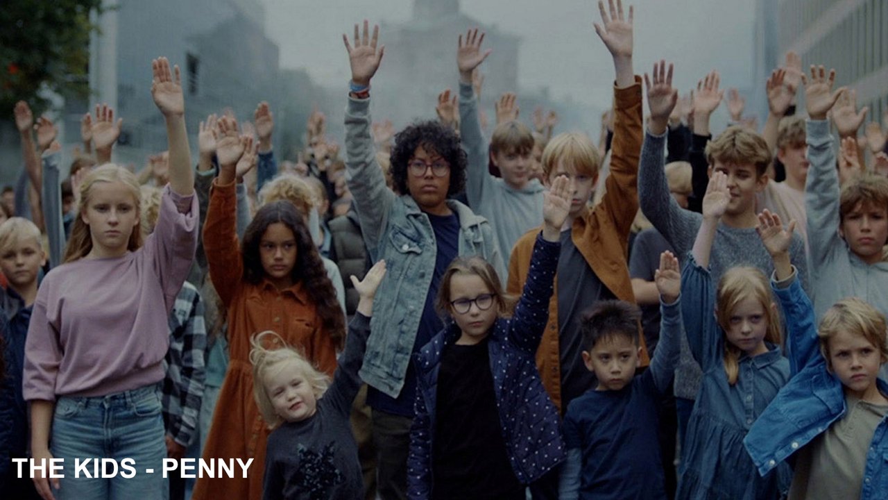 A collection of children looking grimly into the camera and raising their hands